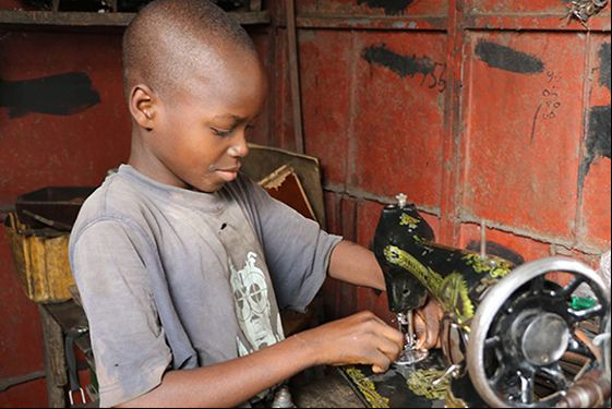 Un niño arregla una máquina de coser en el mercado Dantopka en Cotonou, Benín. Foto Iciar de la Peña-Manos Unidas