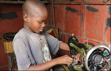 Un niño arregla una máquina de coser en el mercado Dantopka en Cotonou, Benín. Foto Iciar de la Peña-Manos Unidas