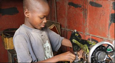 Un niño arregla una máquina de coser en el mercado Dantopka en Cotonou, Benín. Foto Iciar de la Peña-Manos Unidas